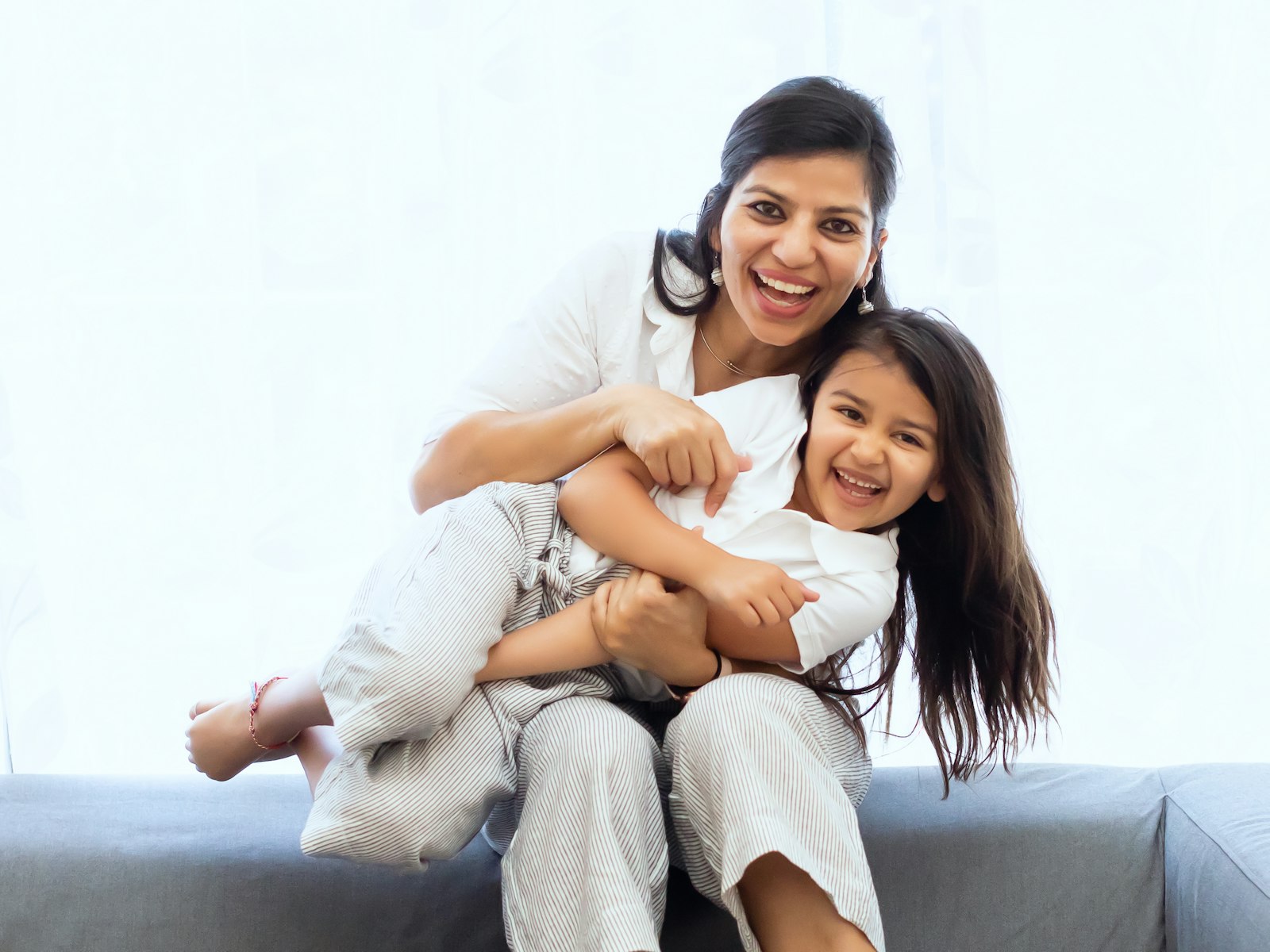 A woman and a laughing child on a sofa